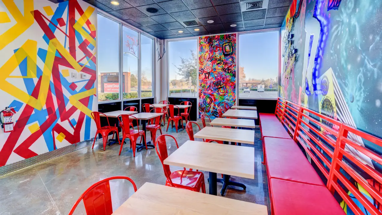 Close up of dining chairs and tables from interior of the fried chicken spot in Missouri City, TX. This images focus more on the a different corner, with a new graffiti wall and window in the frame.
