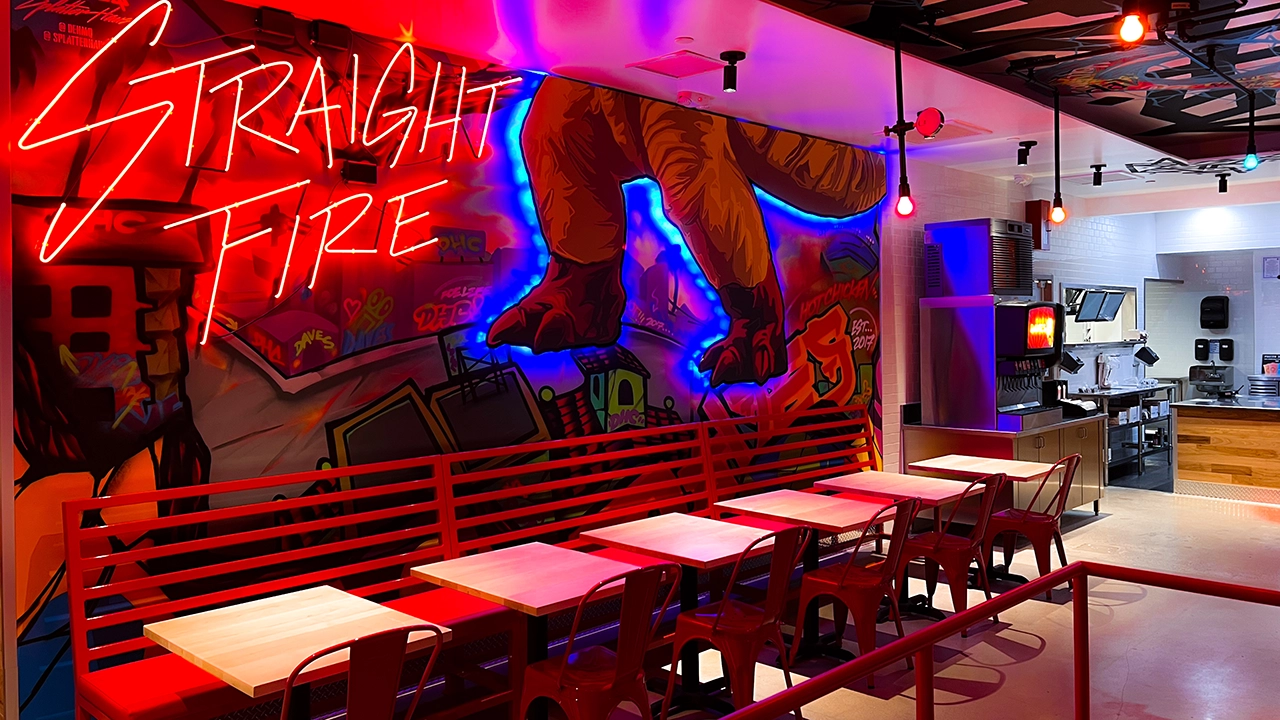 n vibrant interior wall featuring a large graffiti-style mural with bold red and blue colors, depicting oversized hands and the neon-text 