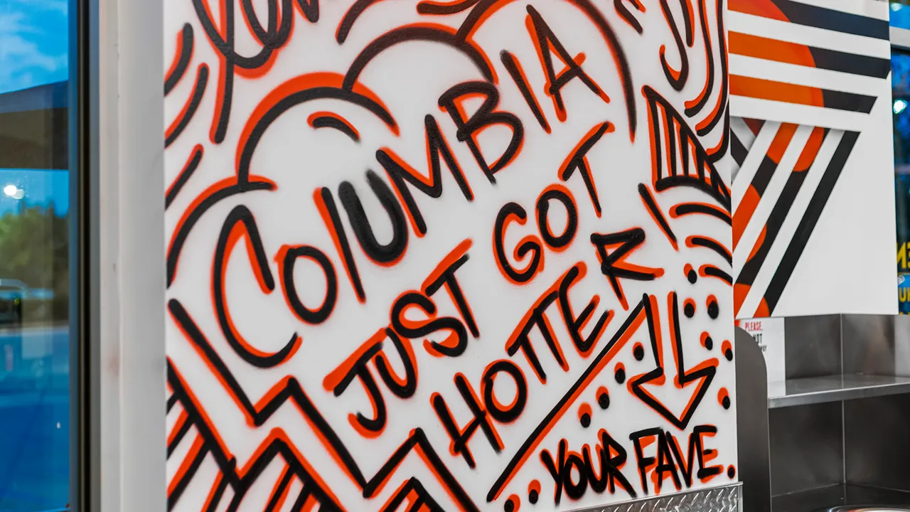 Close-up of graffiti-style mural that reads 'Columbia just got hotter' at Dave's Hot Chicken, SC.