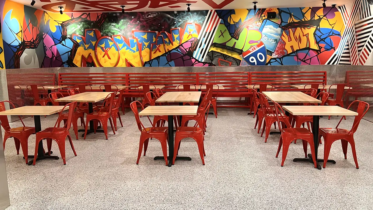 Red bench seating and graffiti-style murals inside Dave's Hot Chicken in Billings, MT