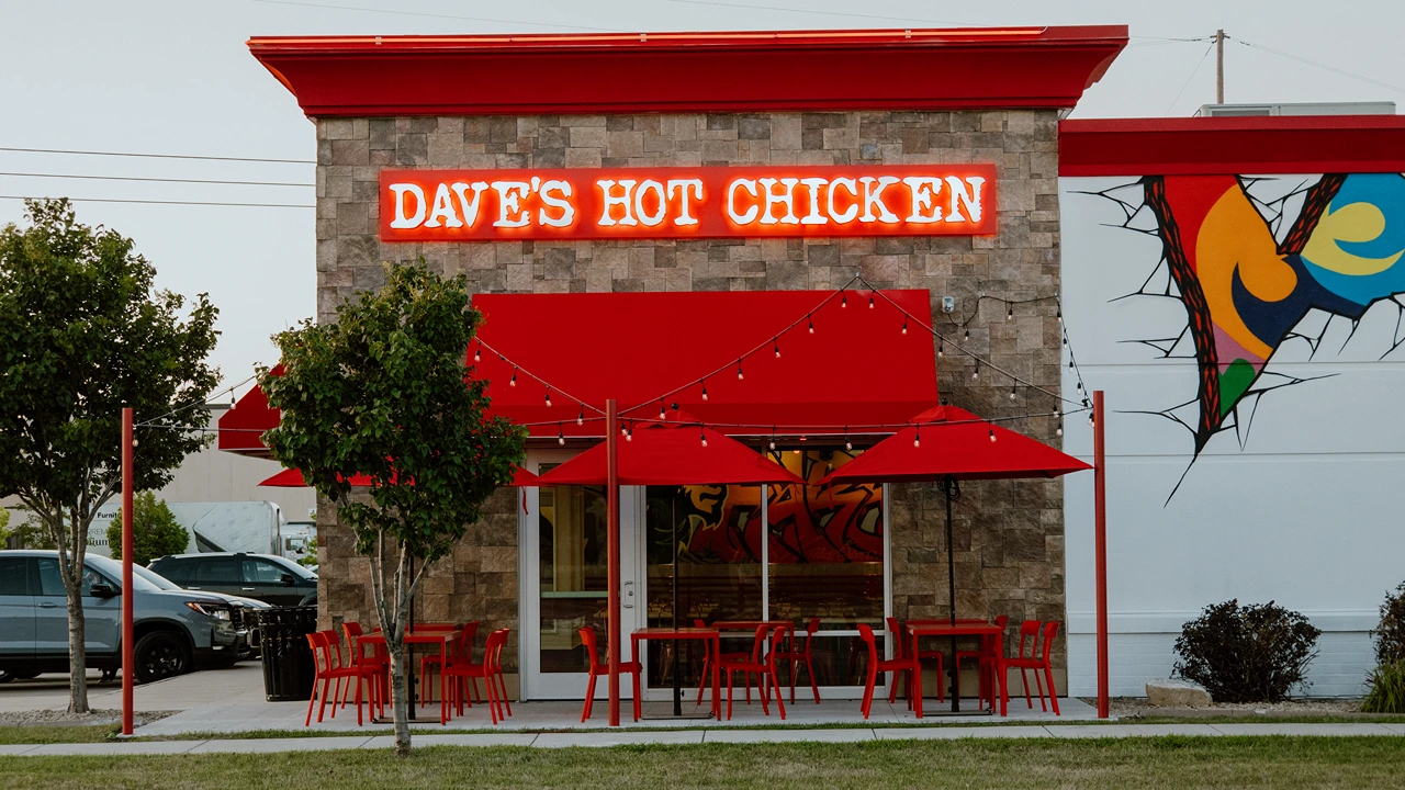 Exterior of Dave's Hot Chicken in Fargo, ND, 45th-street, with red signage and seating under a red canopy.