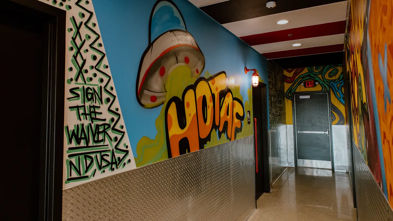 Graffiti art with a UFO and bold text in a hallway at Dave's Hot Chicken in Fargo, ND.