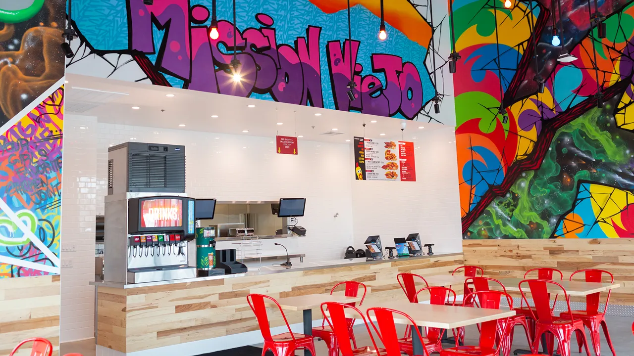 Service counter and seating at Dave's Hot Chicken on Alicia Pkwy, Mission Viejo, CA, showcasing colorful graffiti murals above the counter and wall.