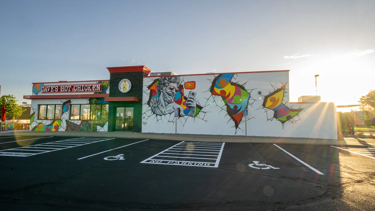 Exterior of Dave's Hot Chicken in Apple Valley, MN, with colorful murals and outdoor seating.