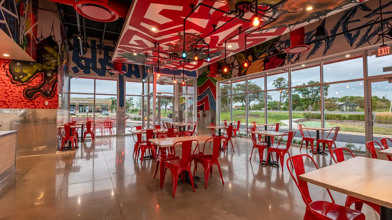 Inside a Dave's Hot Chicken restaurant in Batavia, IL, showcasing the dining area with colorful murals and artwork.