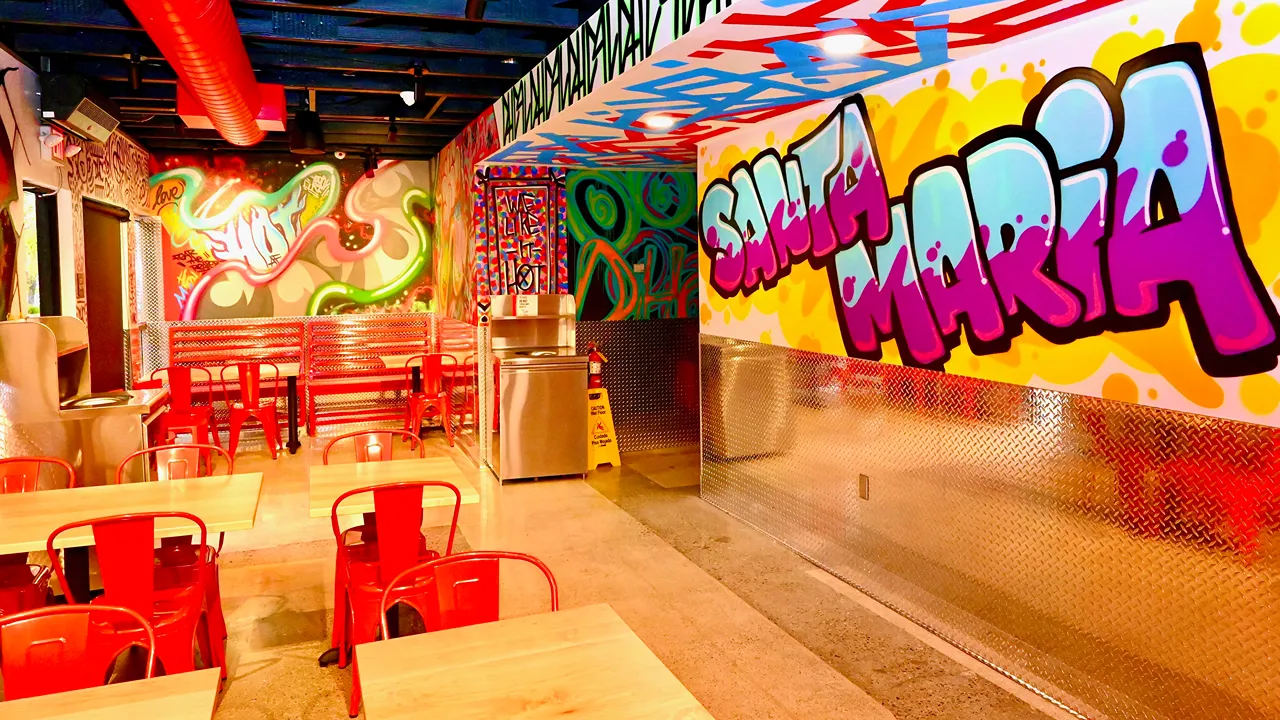 Dining area with colorful artwork and red seating at Dave’s Hot Chicken, Betteravia Rd, Santa Maria, CA.