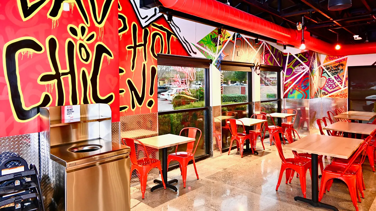 Inside view of seating with red chairs and vibrant graffiti art, including “Santa Maria” text at Dave’s Hot Chicken, Betteravia Rd, Santa Maria, CA.