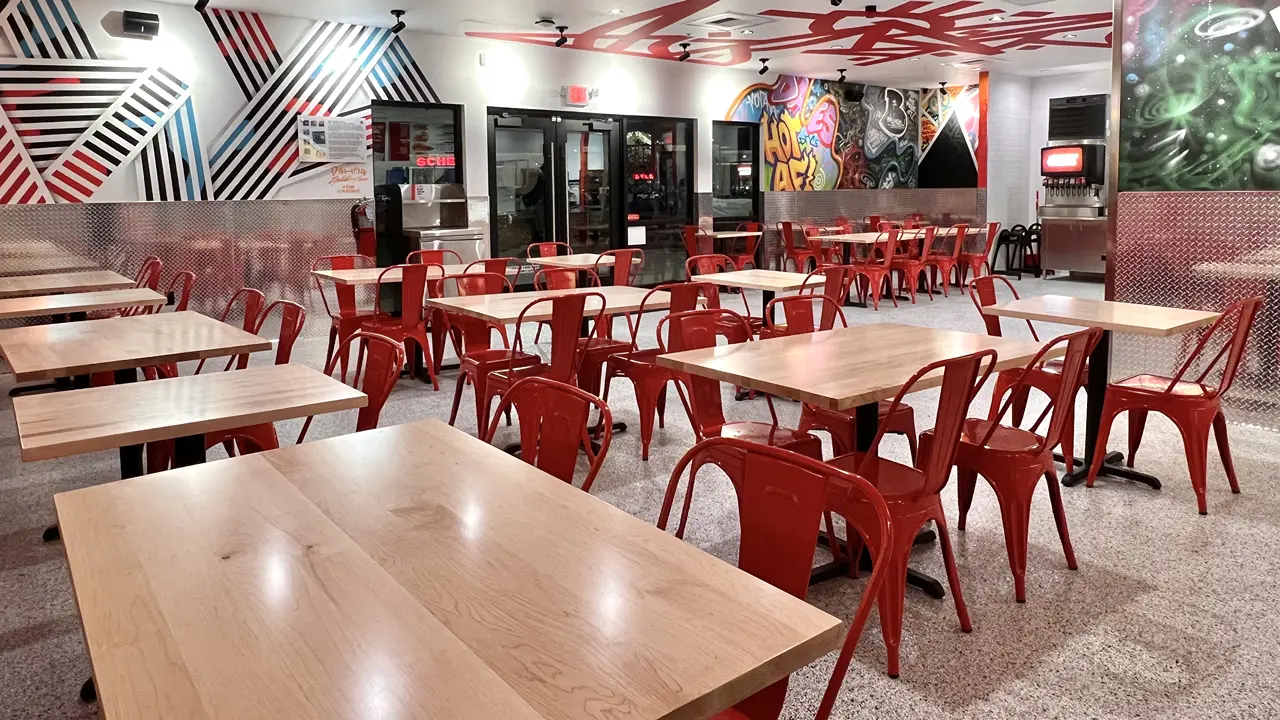 Spacious seating area inside Dave's Hot Chicken in Billings, MT, featuring red chairs and modern wall art.