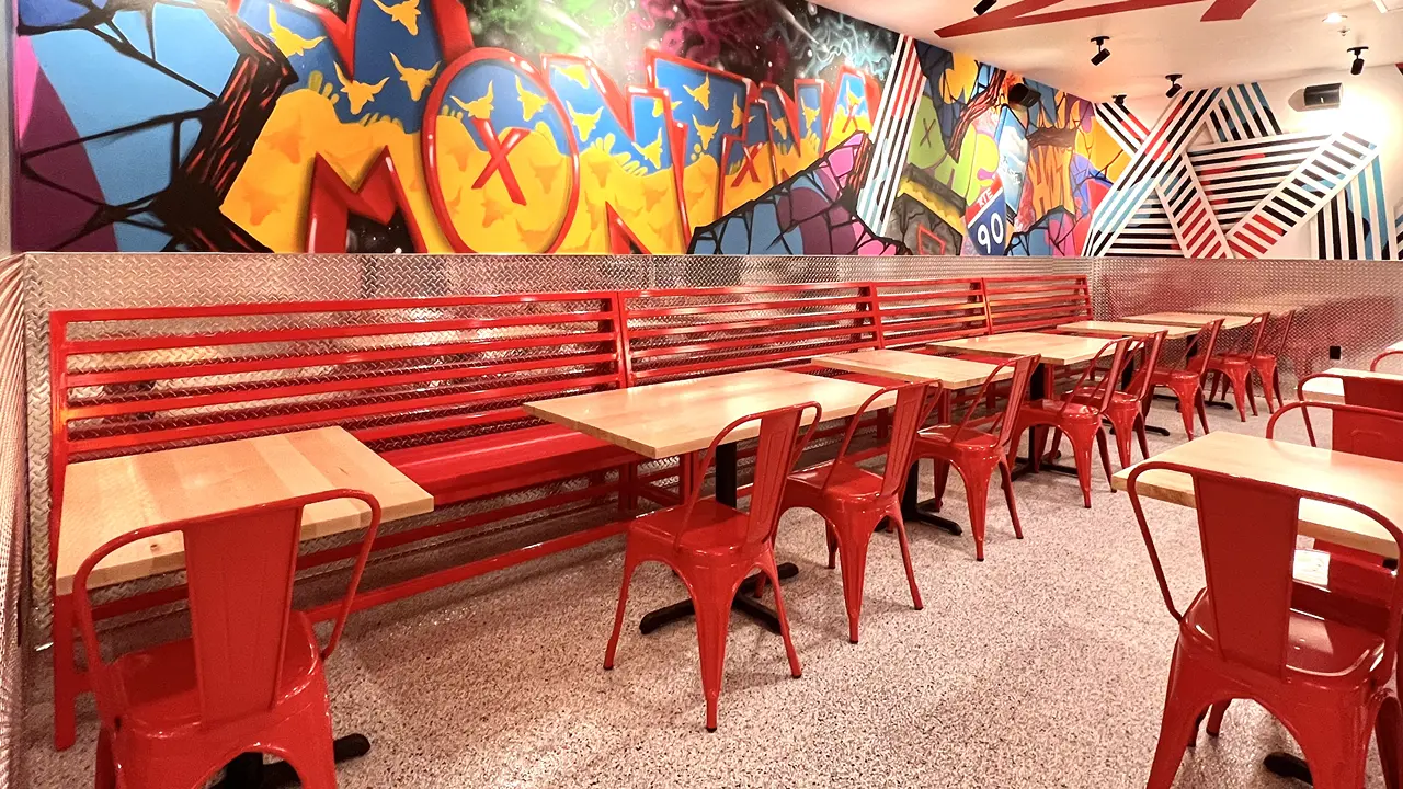 Vibrant mural artwork with red bench seating inside Dave's Hot Chicken in Billings, MT.