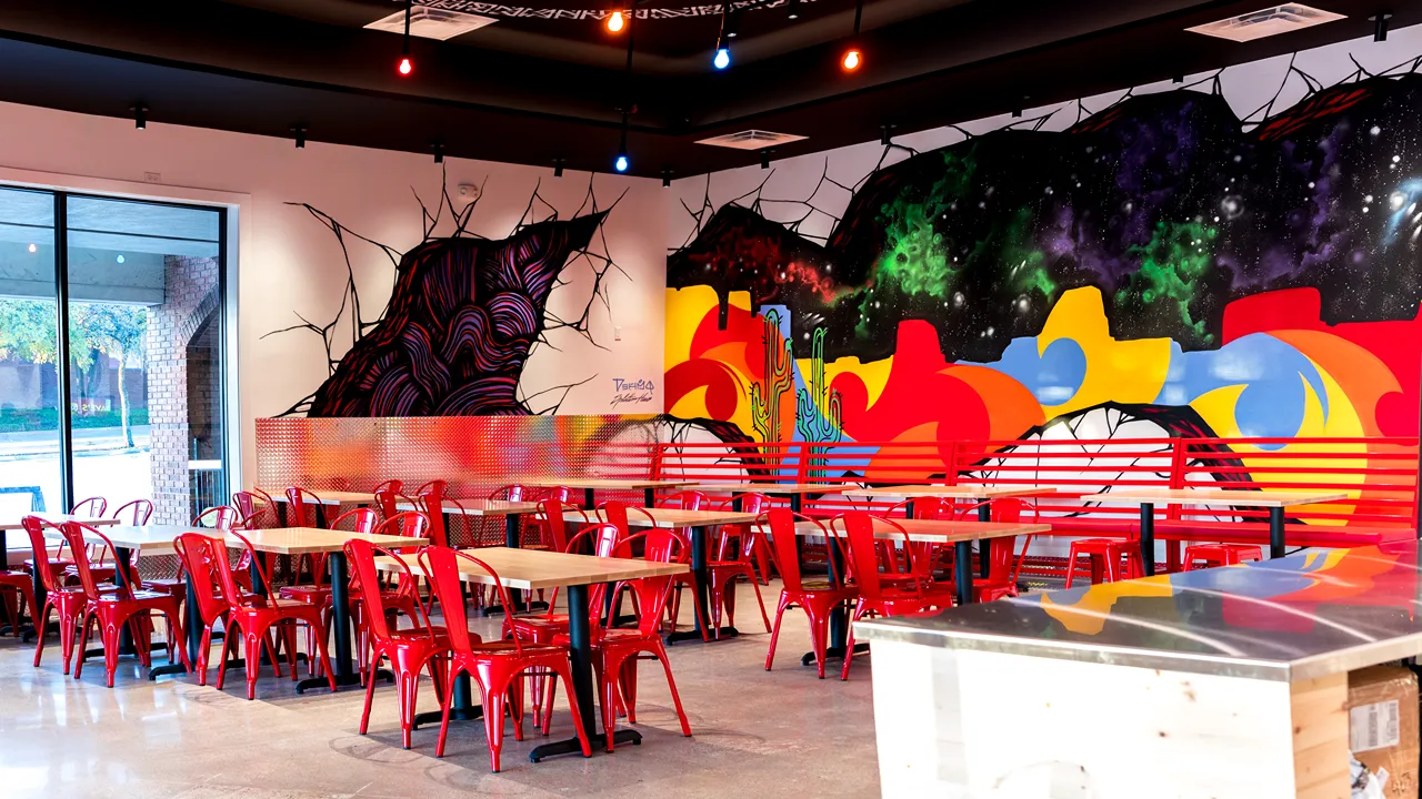 Colorful wall mural and red seating in the dining area at Dave’s Hot Chicken in City View Center, Fort Worth, TX.