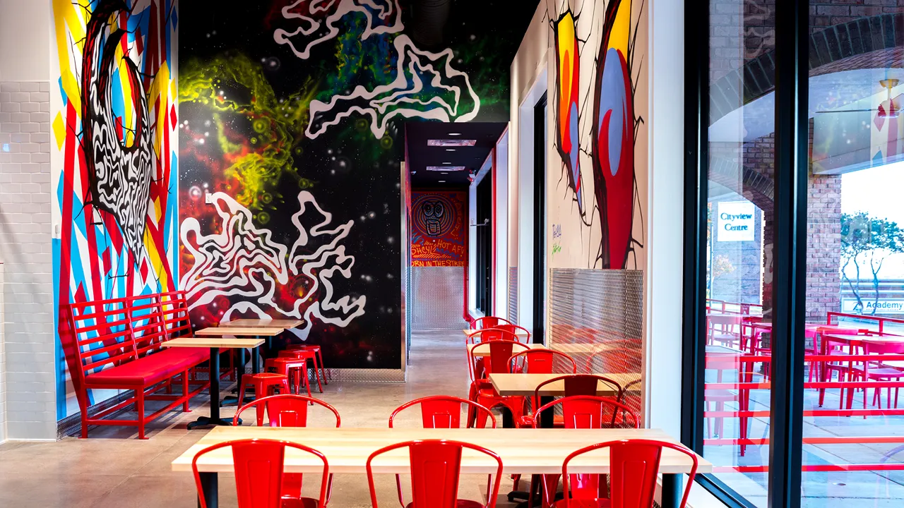 Seating area with red chairs and large windows at Dave’s Hot Chicken in City View Center, Fort Worth, TX.