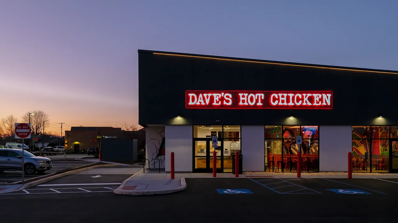 Front view of Dave's Hot Chicken on Carlisle Pike, Mechanicsburg, PA, with a glowing red sign during the evening.