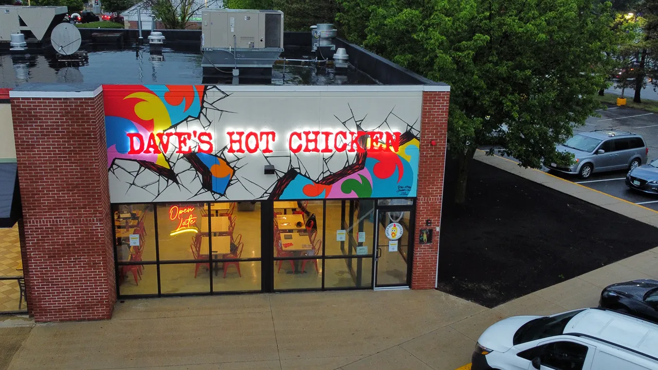 Aerial view of Dave's Hot Chicken in Chelmsford, MA on Drum Hill Road, showing a colorful exterior and rooftop equipment.