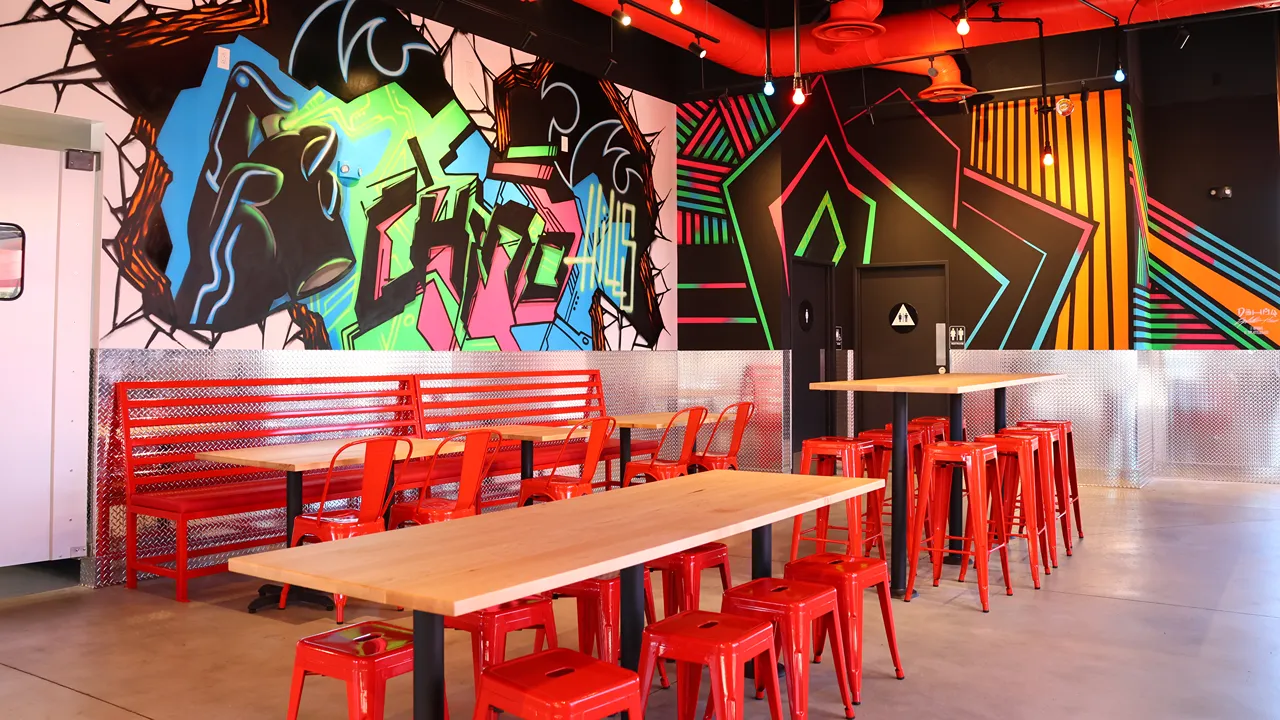 Dave's Hot Chicken Chino Hills, CA interior with red seating and colorful wall mural.