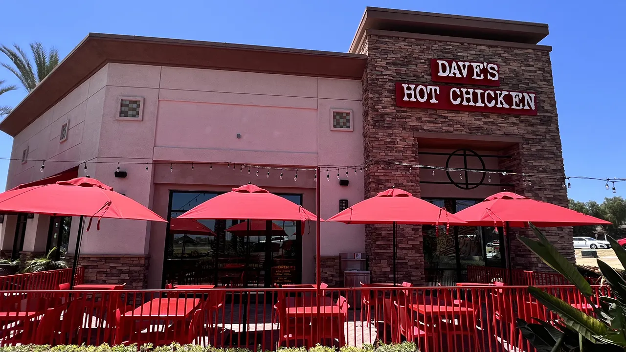 Dave's Hot Chicken Chino Hills, CA exterior with red umbrellas and outdoor seating.