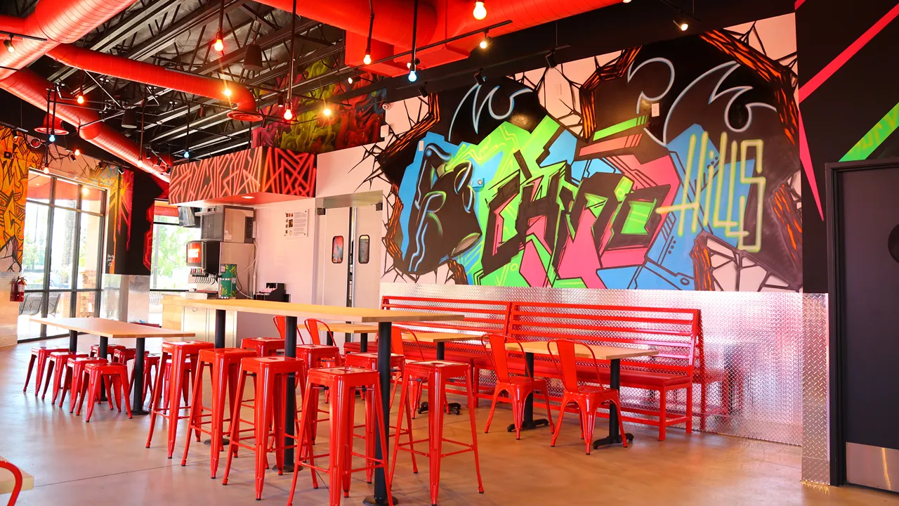 Dave's Hot Chicken Chino Hills, CA interior with red seating and a vibrant, colorful mural on the wall.