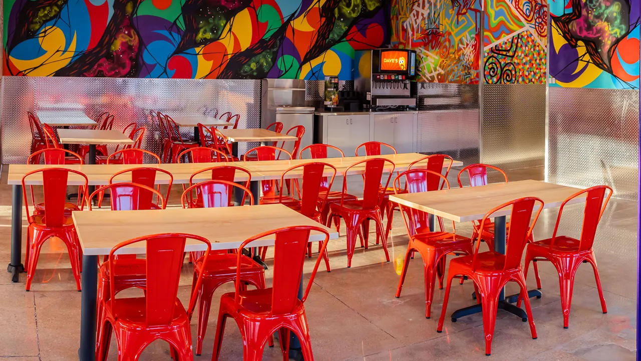 Seating area with red chairs and vibrant murals at Dave’s Hot Chicken in Fort Worth, TX on Cockrell Ave.