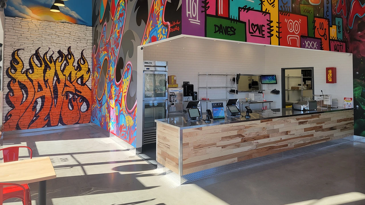 Dave's Hot Chicken counter with colorful murals and artwork inside the Amsterdam, NY location.