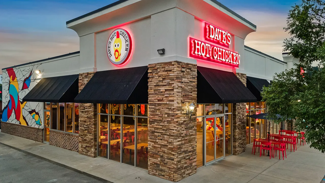 Exterior view of Dave's Hot Chicken with neon signage and outdoor seating on Devine Street, Columbia, SC.