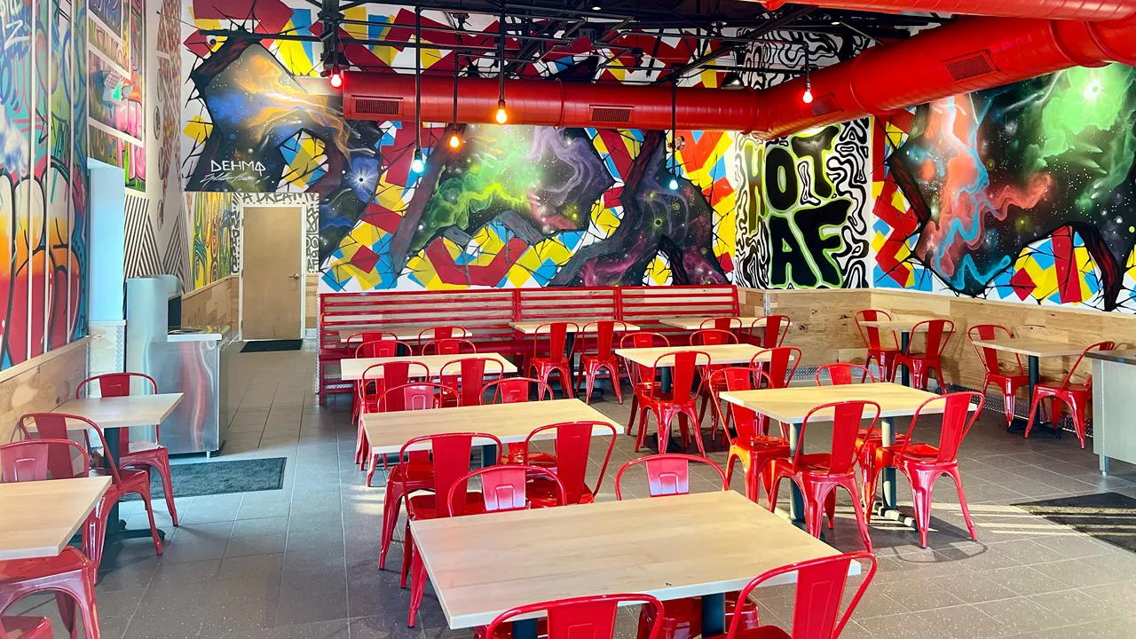 Bright and colorful dining area with red chairs and tables at Dave's Hot Chicken on E. Fowler Ave, Tampa, FL near USF.