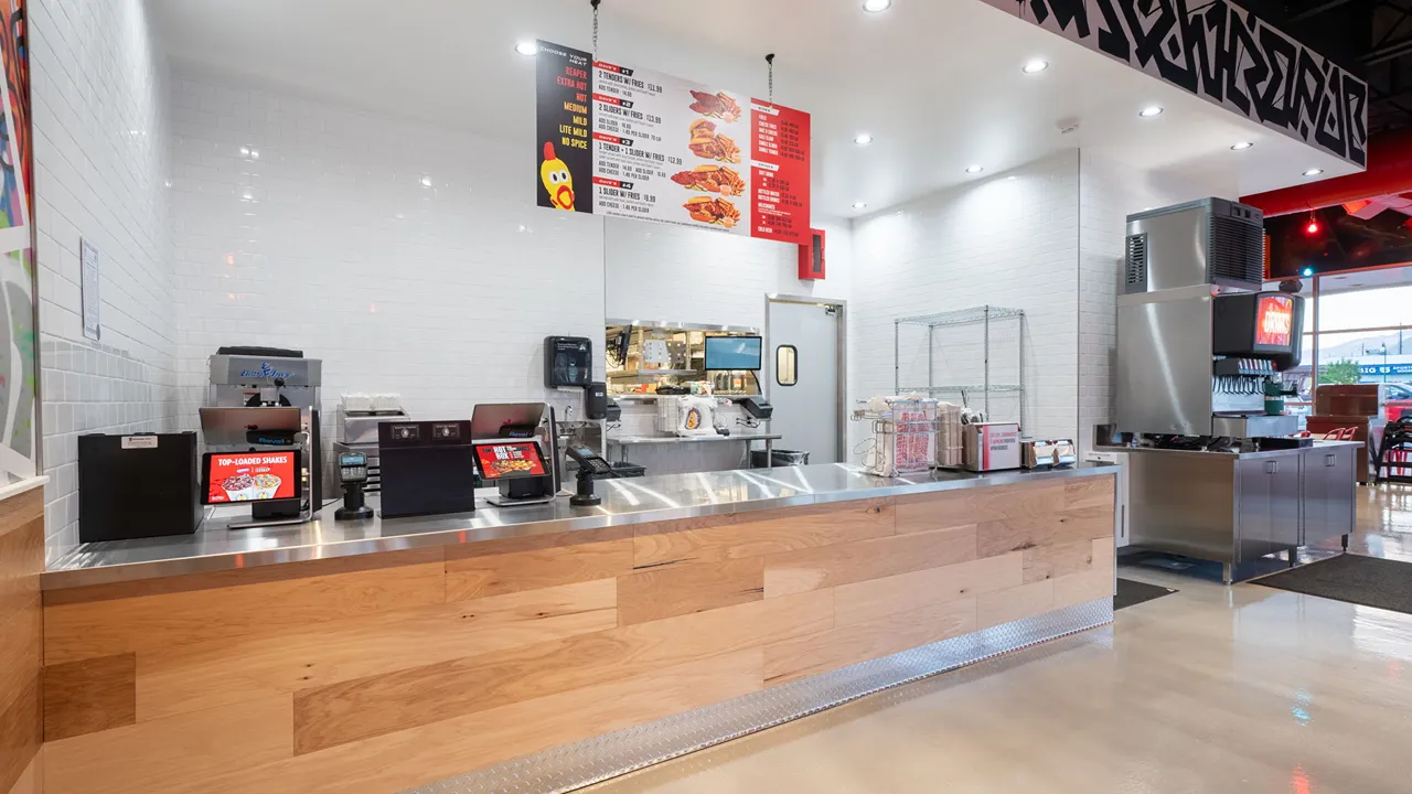 The ordering counter at Dave’s Hot Chicken, Orem, Utah on E. University Pkwy, featuring a bright menu and sleek modern design.