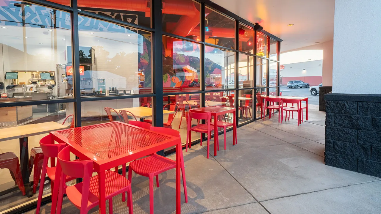 Red outdoor seating area along the glass windows at Dave’s Hot Chicken, located on E. University Pkwy in Orem, UT.