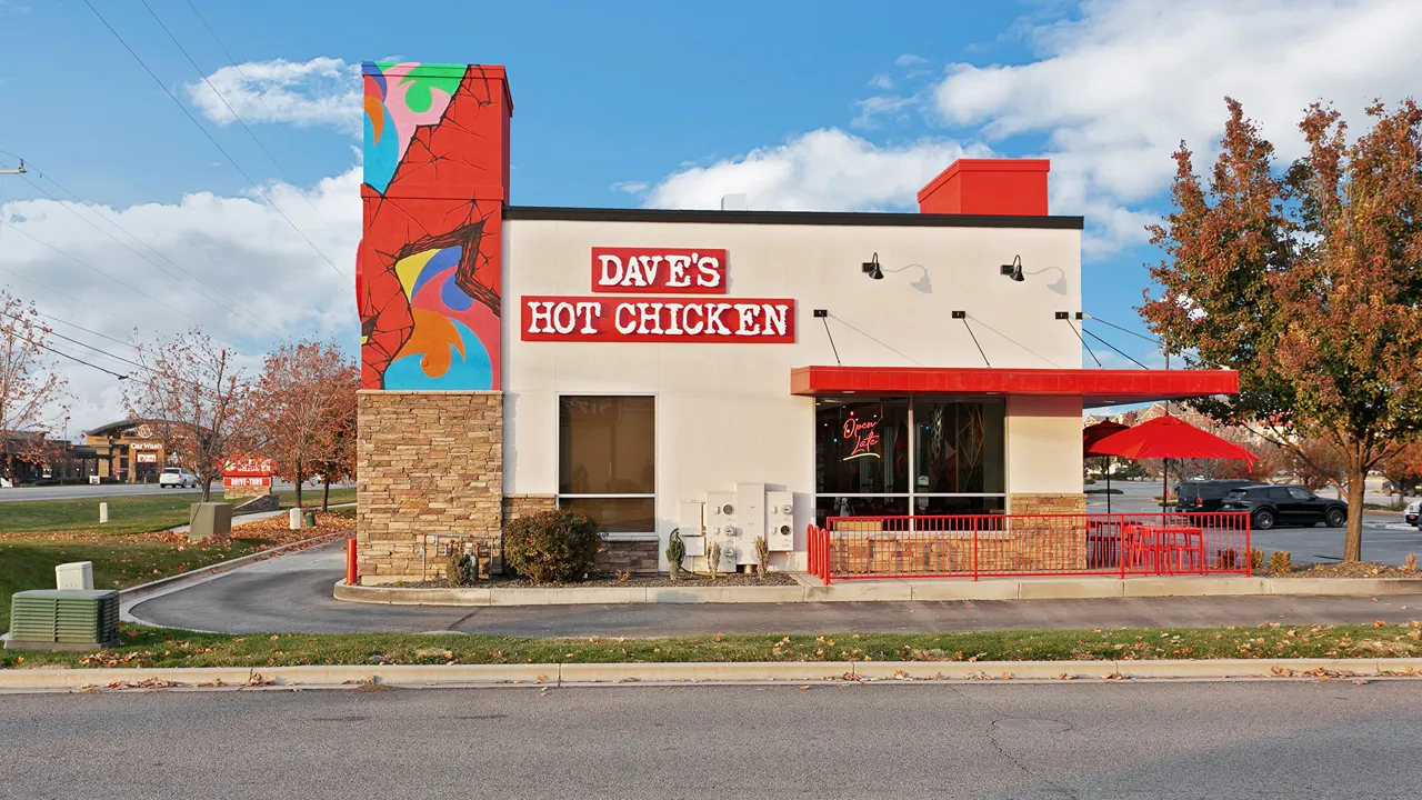 The exterior view of Dave's Hot Chicken on Eagle Rd, Meridian, ID, showcasing bold red signage and a bright mural.