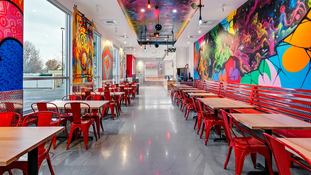 Spacious seating with colorful graffiti artwork inside Dave's Hot Chicken on Eagle Rd, Meridian, ID.