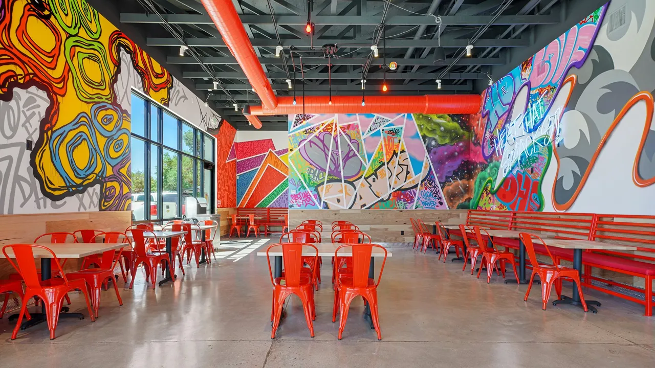 Spacious dining area with vibrant wall murals and large windows at Dave’s Hot Chicken in the Sugar House District of Salt Lake City, UT.