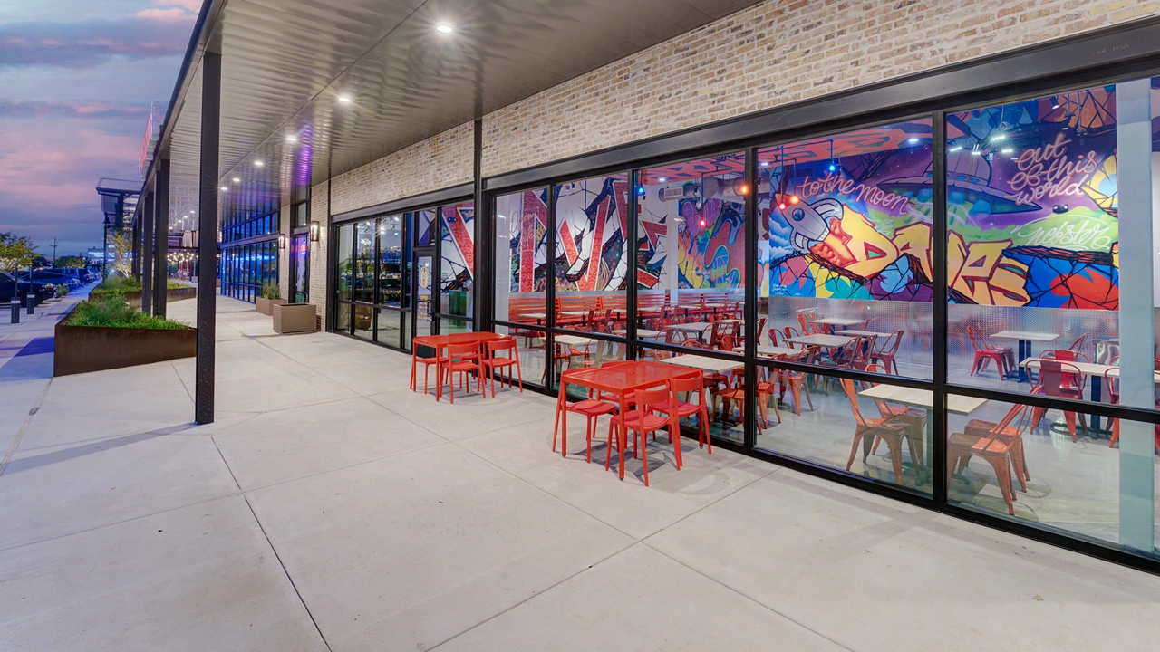 Exterior evening shot of Dave's Hot Chicken, Eastfield Dr, Webster, TX, Baybrook location with outdoor seating.