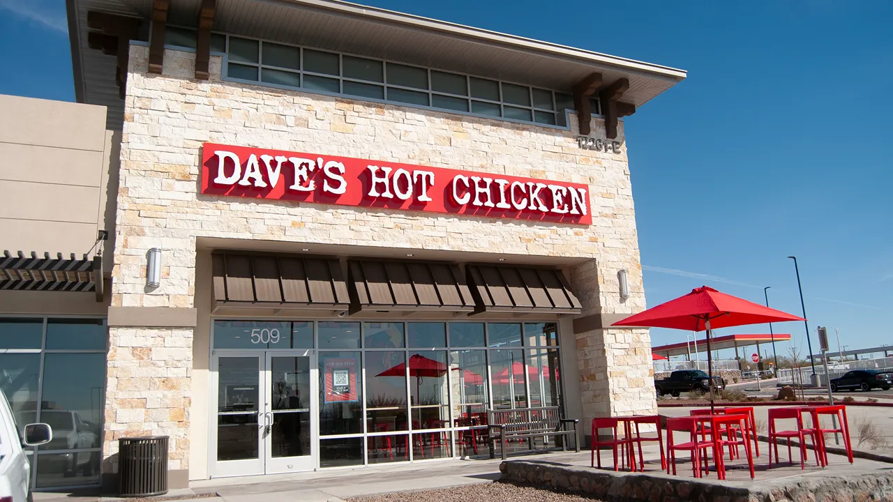 Exterior of Dave's Hot Chicken with a stone facade and bright red outdoor seating area in El Paso, TX., Eastlake Blvd.