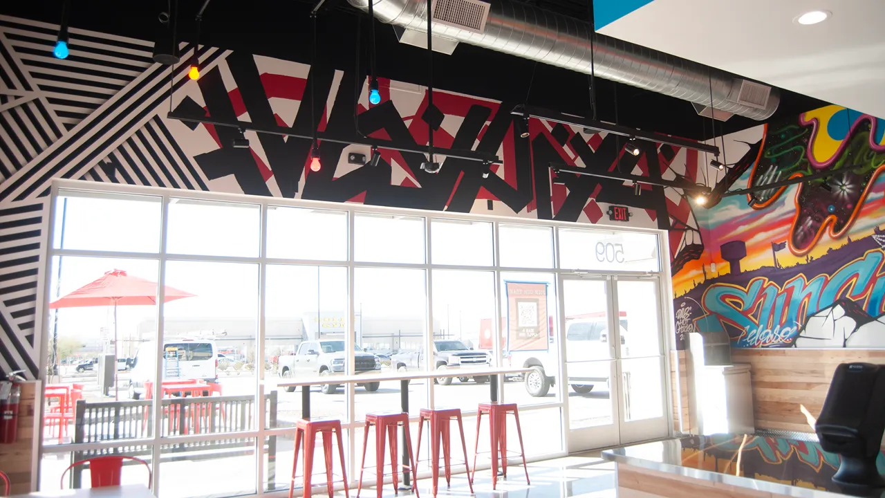 Seating area with bar stools and tables by the window inside Dave's Hot Chicken in El Paso, TX., Eastlake Blvd.