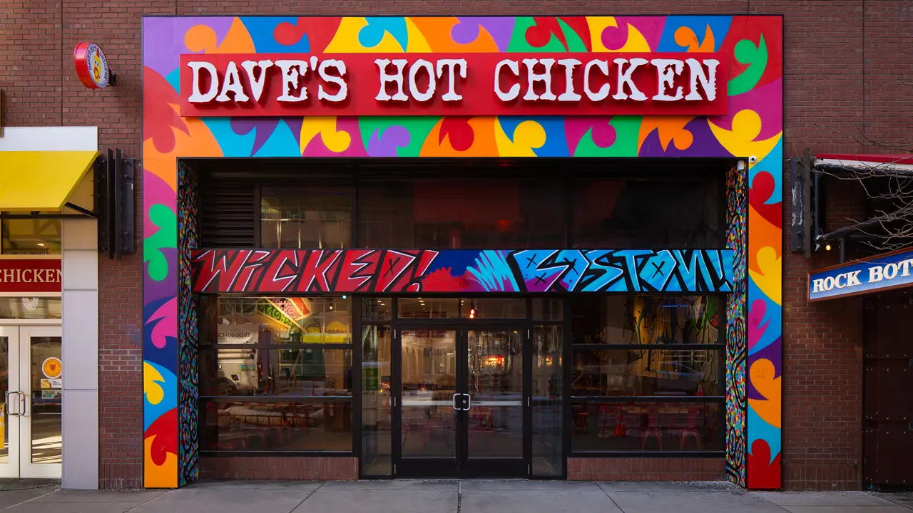 The exterior of Dave's Hot Chicken on Stuart Street in Boston, MA, at City Place, with its vibrant, colorful facade and bold signage.