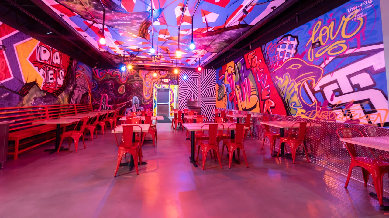 Interior of Dave’s Hot Chicken in St. Paul, MN, showcasing vibrant seating area with artistic ceiling design and wall murals.