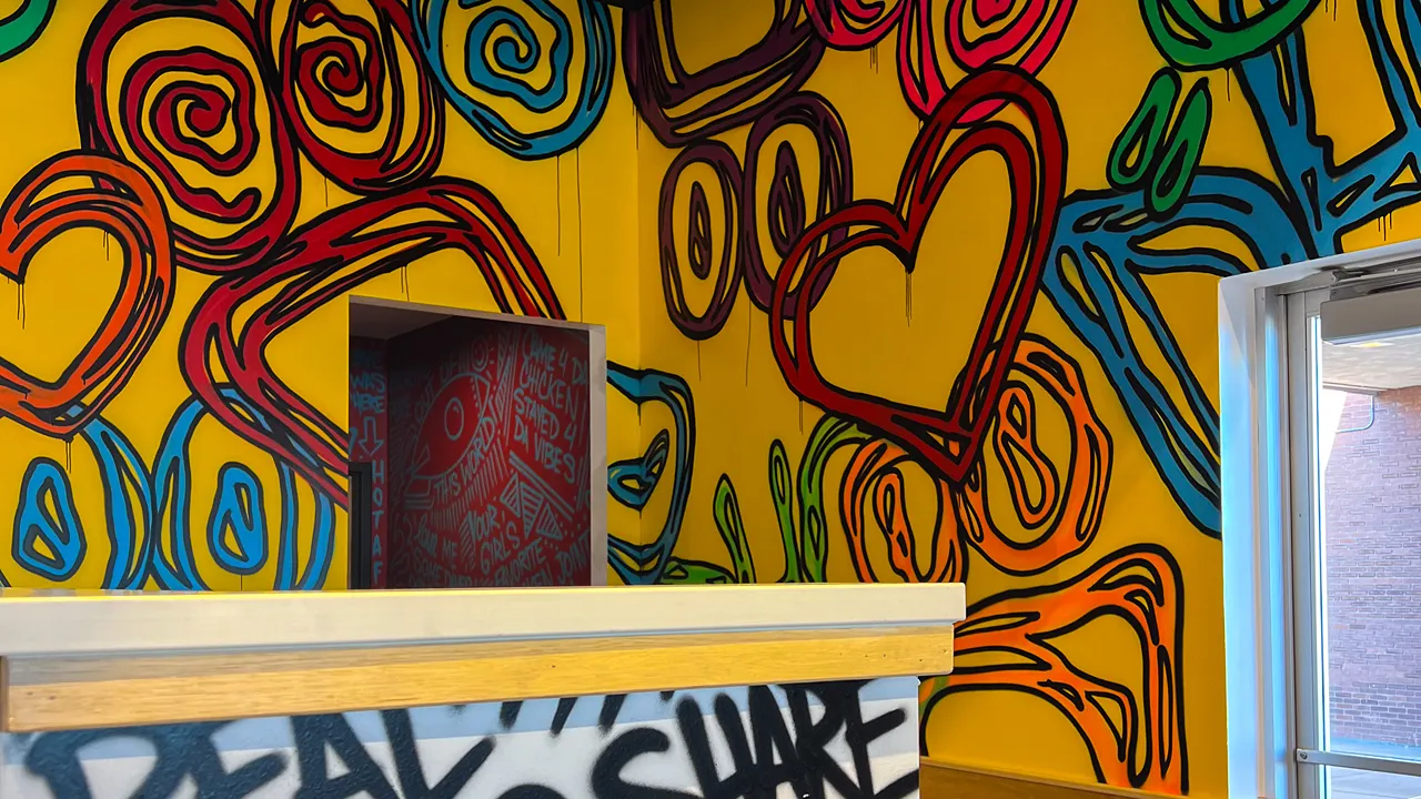 A bold yellow wall design inside Dave's Hot Chicken on Fort Union Blvd, Midvale, UT, with abstract and colorful patterns.