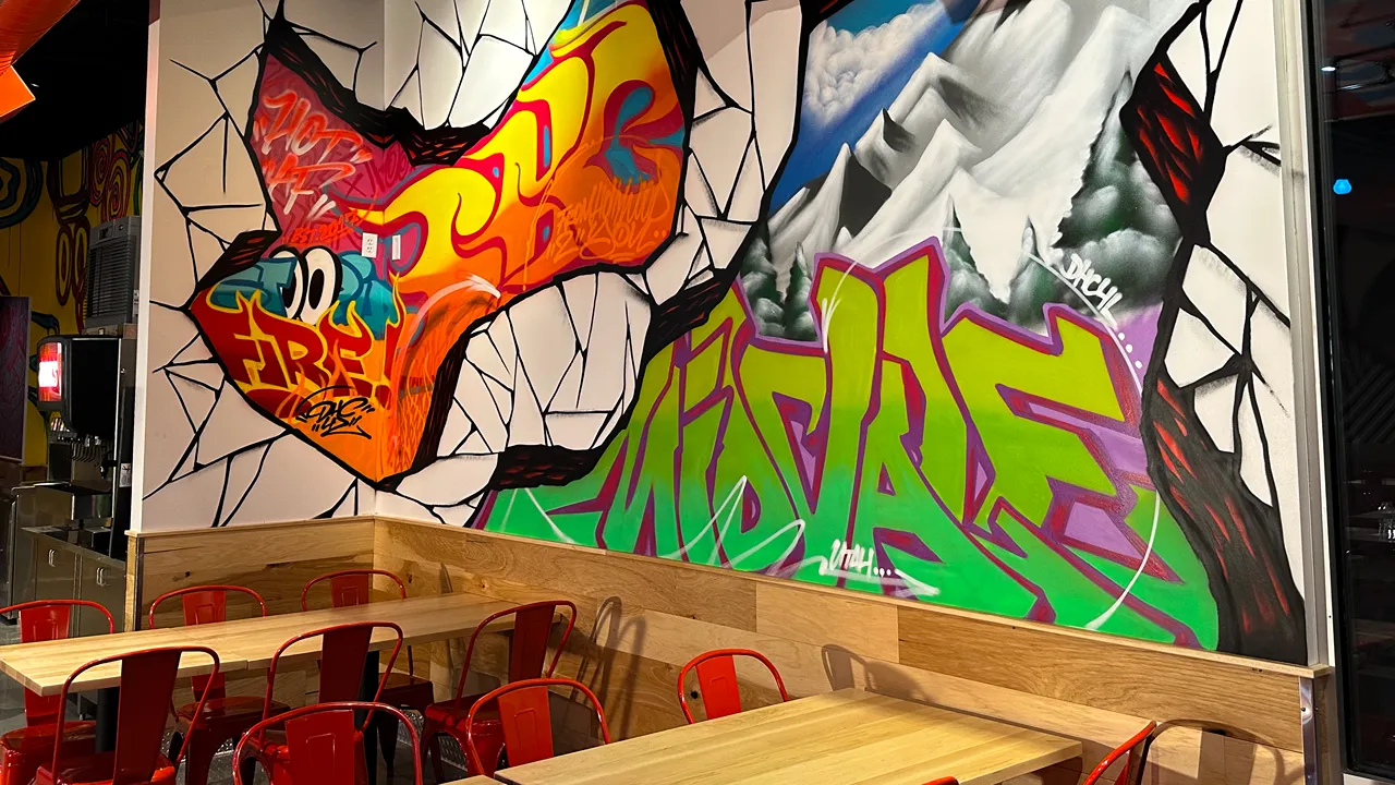 Bright graffiti-style wall art inside Dave's Hot Chicken on Fort Union Blvd, Midvale, UT, featuring colorful designs.