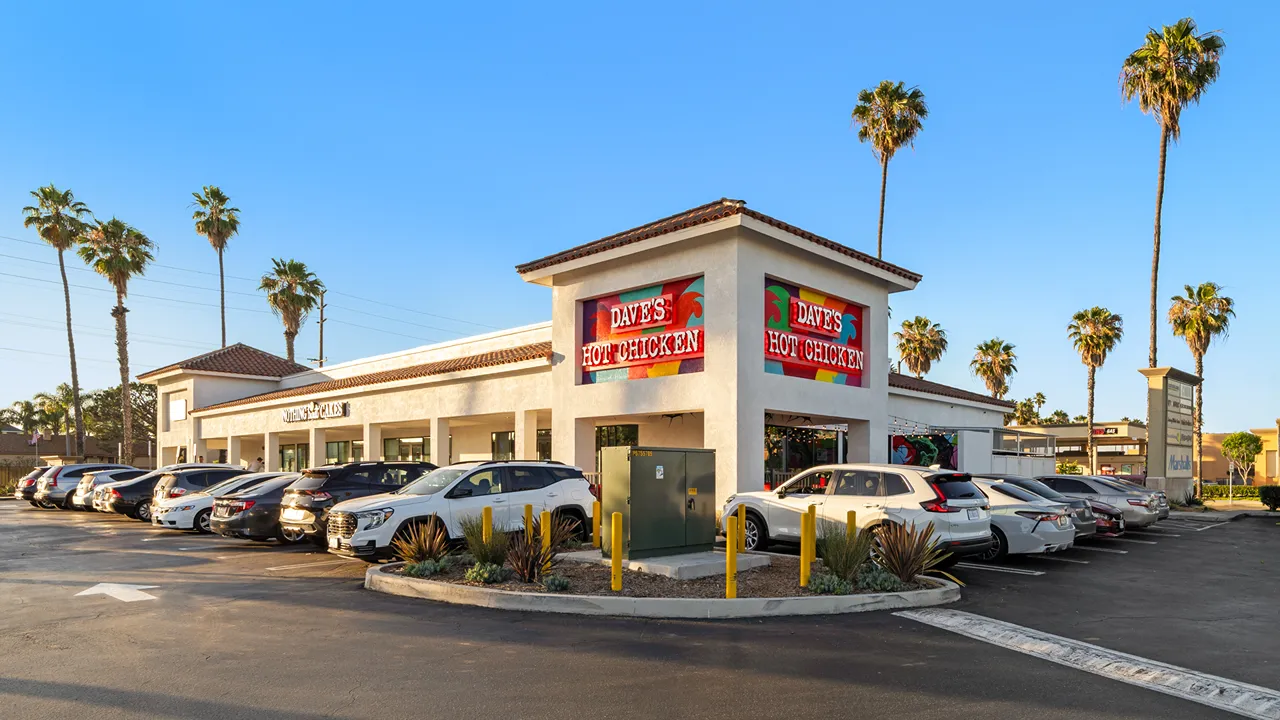 Exterior view of Dave's Hot Chicken at Circle Center West, Long Beach, with palm trees in the background.