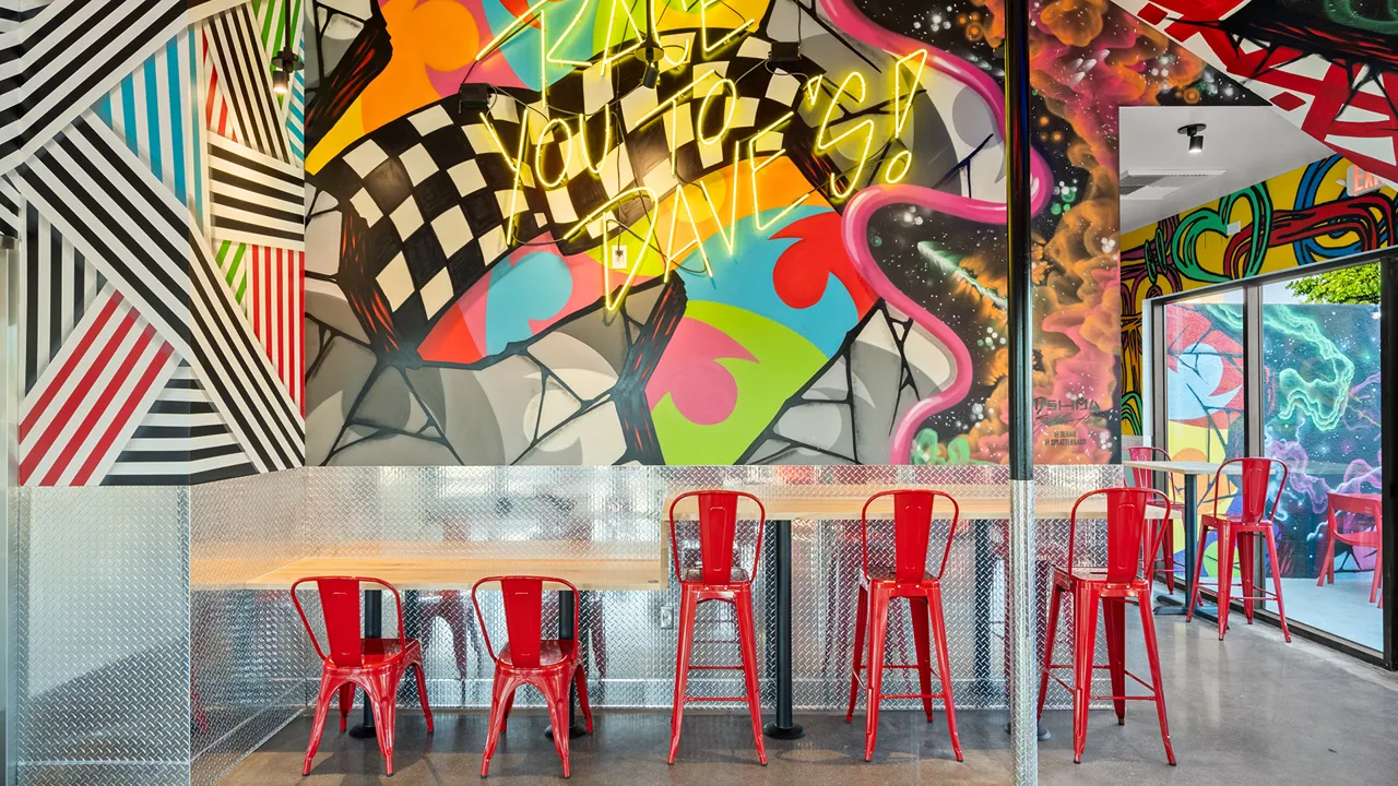 Bold stripe mural with red chairs against the wall at Dave's Hot Chicken, Long Beach, CA.