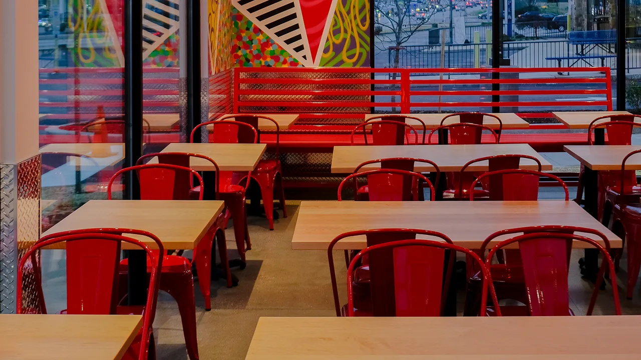 Seating arrangement with red chairs and tables by the windows at Dave's Hot Chicken, Loucks Rd., York, PA