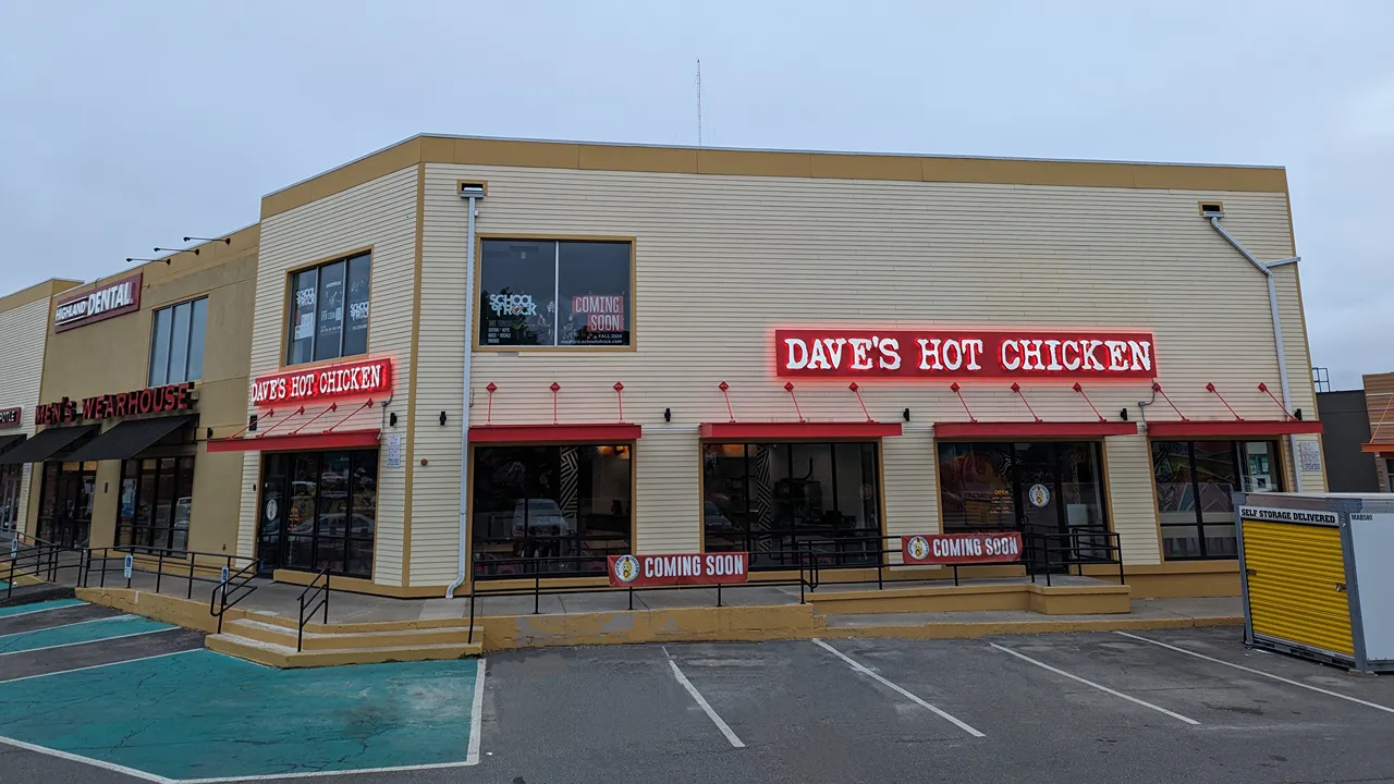 Exterior view of Dave's Hot Chicken on Mystic Valley Pkwy, Medford, MA, with large signage and adjacent storefronts.