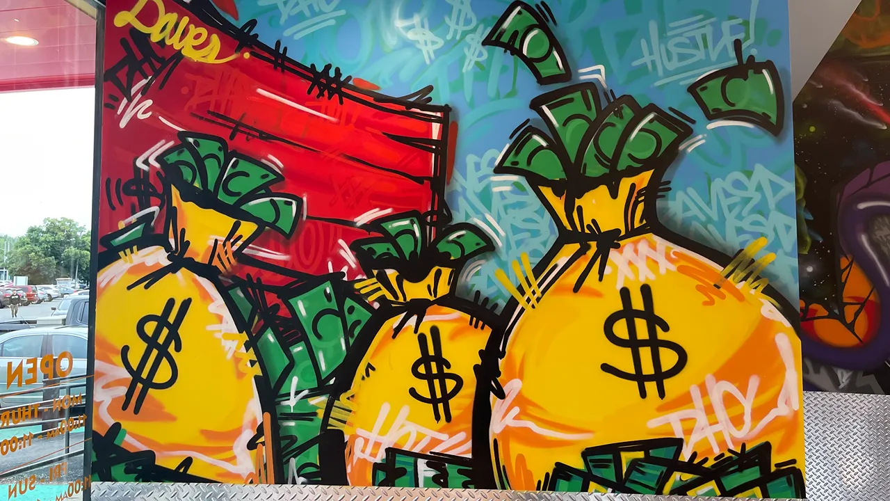 Colorful mural of dollar bags and graffiti art inside Dave's Hot Chicken on Mystic Valley Pkwy, Medford, MA, adding a lively touch to the decor.