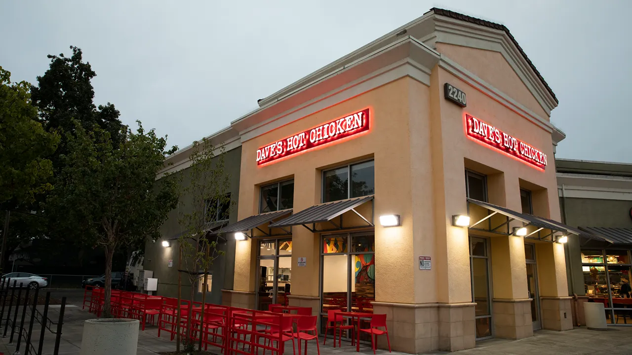 Nighttime view of Dave's Hot Chicken on Mendocino Avenue in Santa Rosa, CA, featuring illuminated signage and outdoor seating.