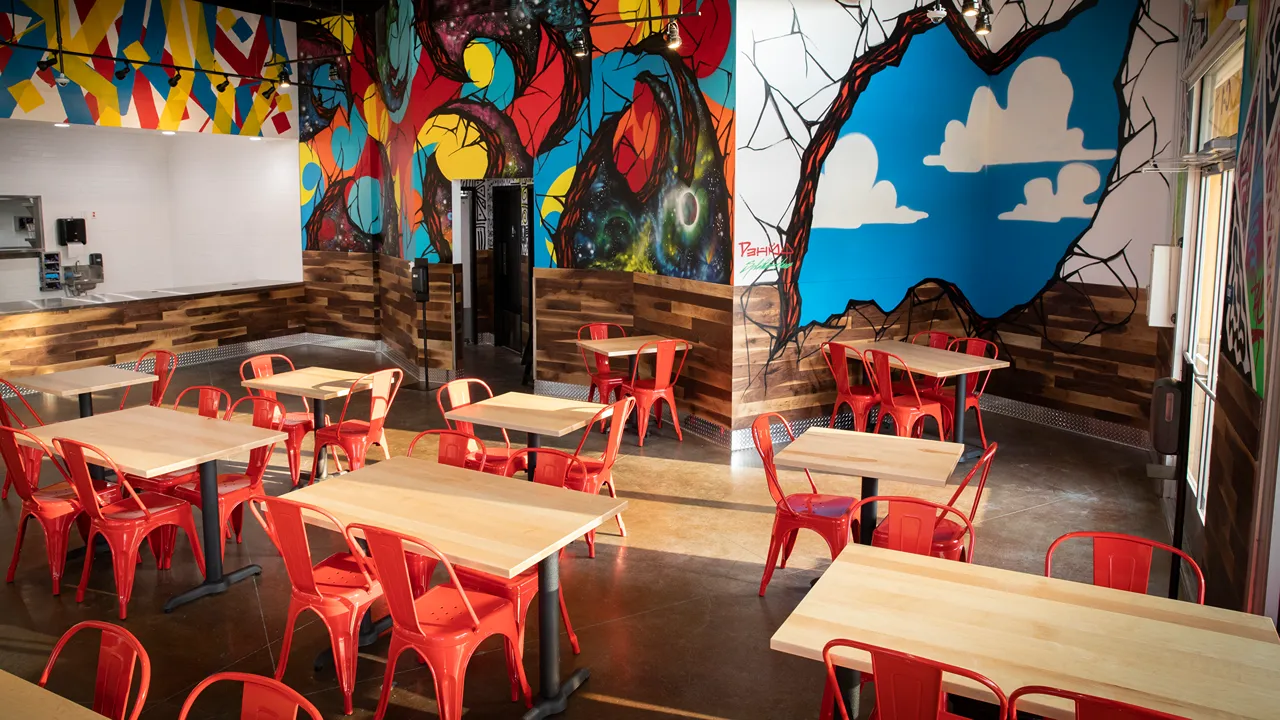 Dining area with red chairs and wooden tables at Dave's Hot Chicken on Mendocino Avenue in Santa Rosa, CA.