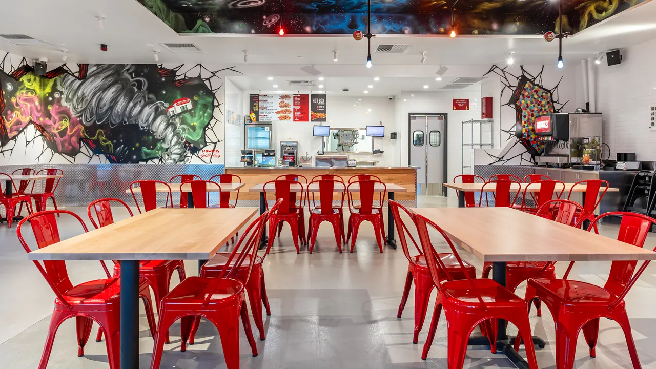 Dining area at Dave's Hot Chicken on Metcalf Avenue in Overland Park, Kansas, featuring bright murals and red seating with wooden tables