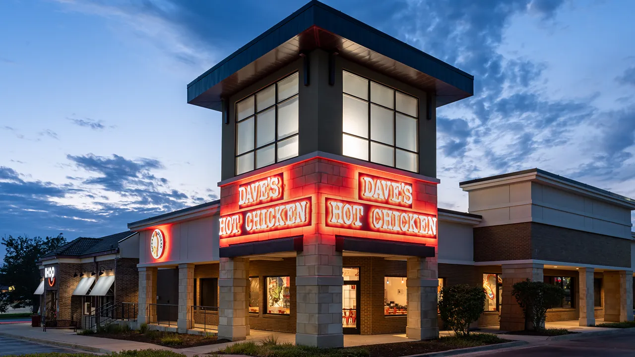 Dave's Hot Chicken restaurant on Metcalf Avenue in Overland Park, Kansas, at night, with glowing signage.