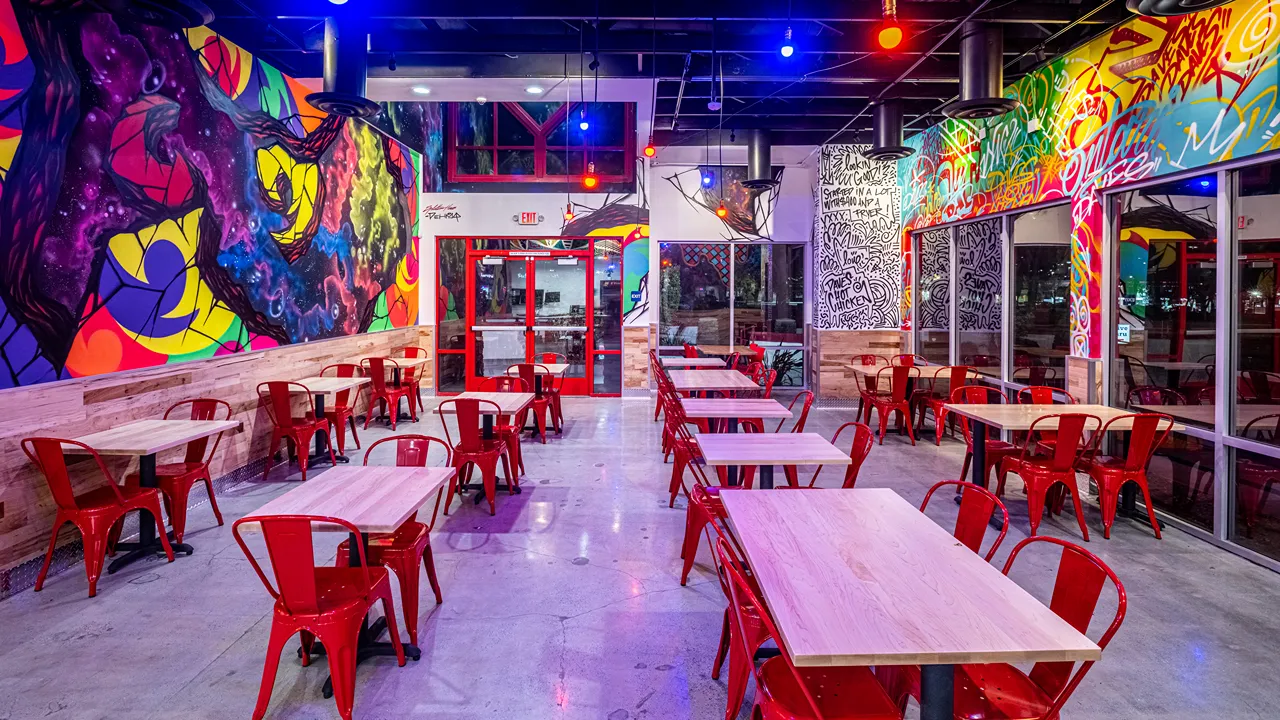 Bright interior seating area with red chairs and abstract wall art at Dave's Hot Chicken, Milliken Ave, Ontario, CA.