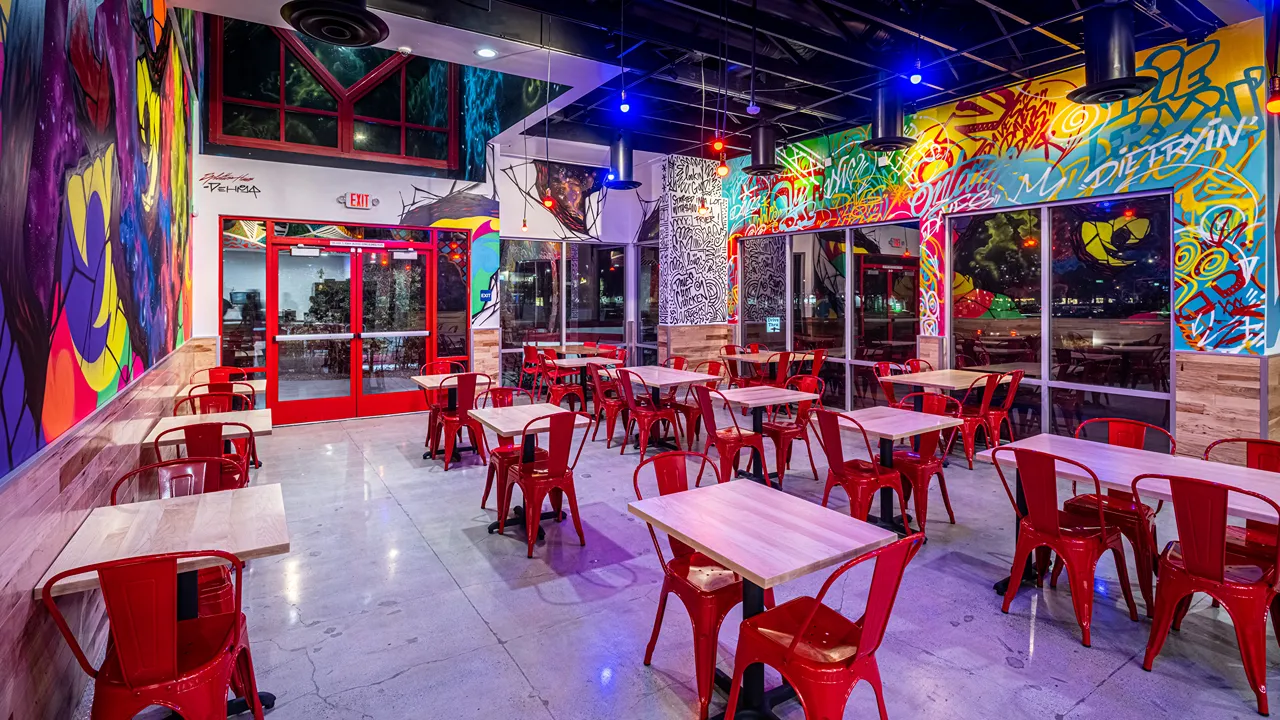 Spacious indoor dining area with colorful wall art and red seating at Dave's Hot Chicken, Milliken Ave, Ontario, CA.