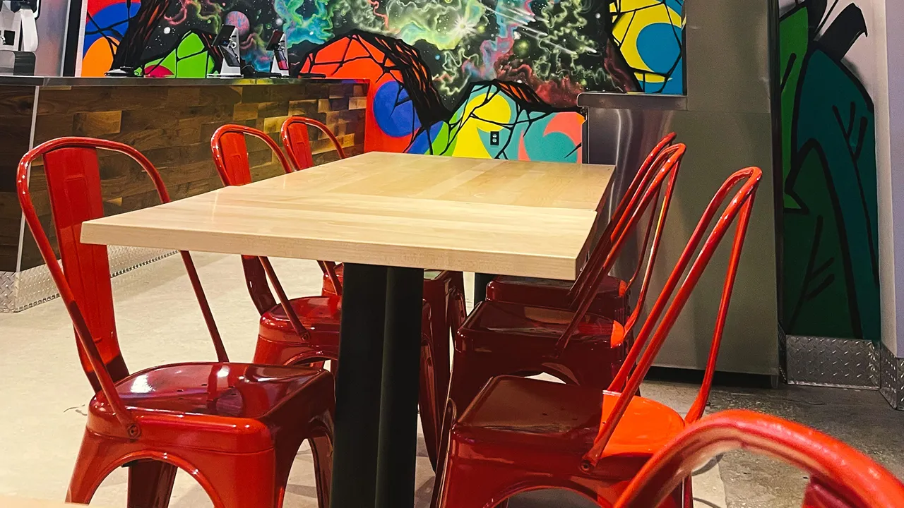 Indoor table seating next to colorful wall art at Dave's Hot Chicken on N. Alafaya Trail, Waterford Lakes, Orlando, FL.