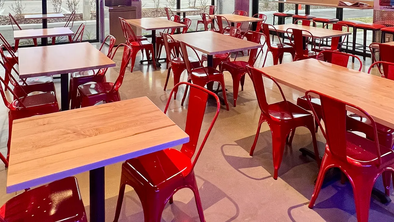 Close-up view of the seating arrangement inside Dave's Hot Chicken on N Dale Mabry Hwy in Tampa, FL, featuring red metal chairs.