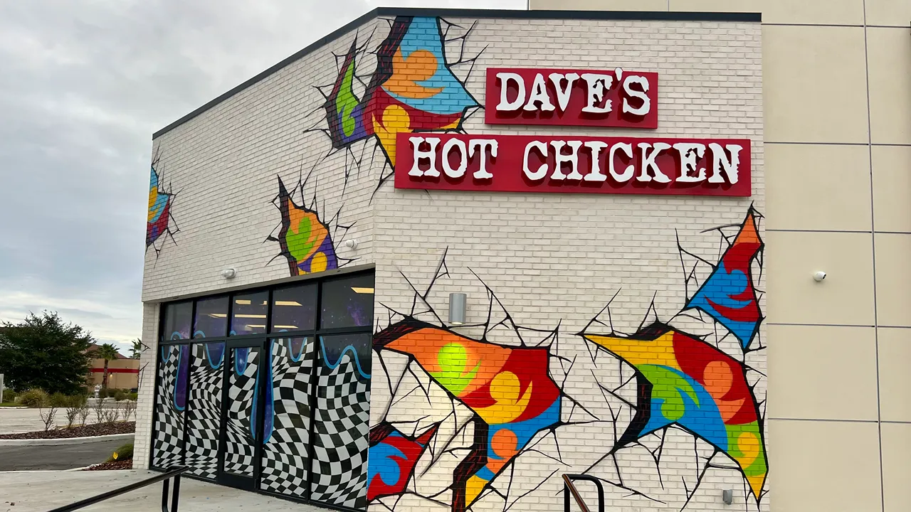 Exterior view of Dave's Hot Chicken on N Dale Mabry Hwy in Tampa, FL, with vibrant graffiti and store signage.